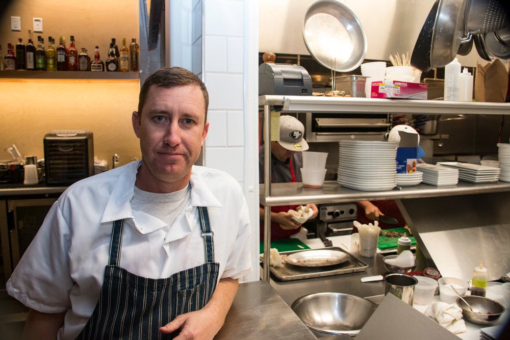 Chef Mike Mullens standing outside kitchen at Perch + Plow restaurant.