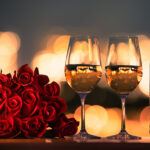 Romantic dinner date night with roses and wine on the table and city lights in the background.